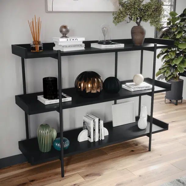 a black shelf with books, vases and other items on it in a living room