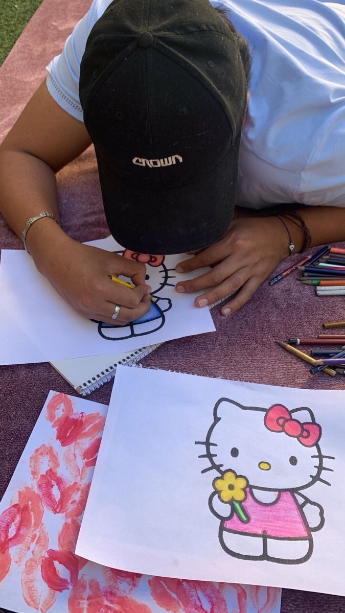 a person sitting at a table with some art supplies and papers on top of it