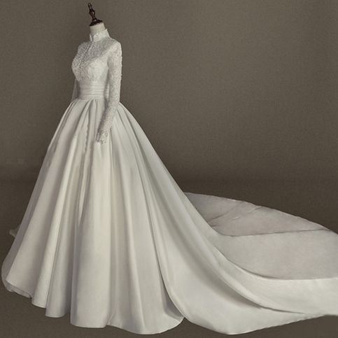 a white wedding dress on display in front of a gray background with an object to the side