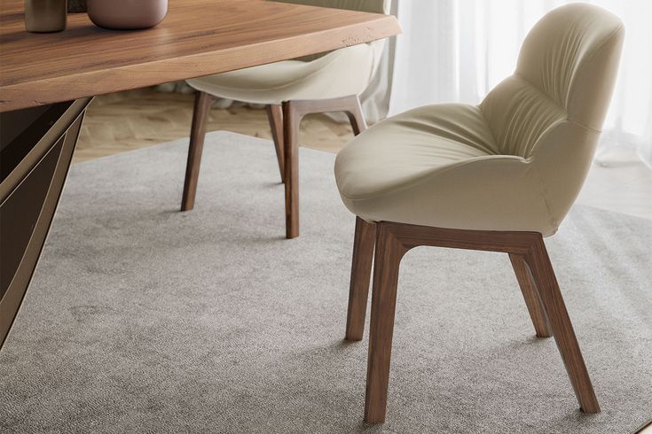 a chair sitting on top of a carpeted floor next to a table with a vase