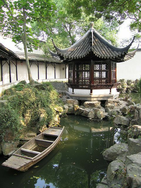 there is a small boat in the water near a building with a pagoda on top