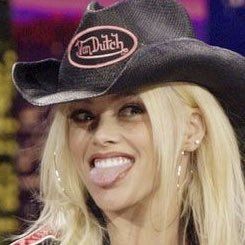 a woman wearing a cowboy hat on top of a tv set with her tongue out