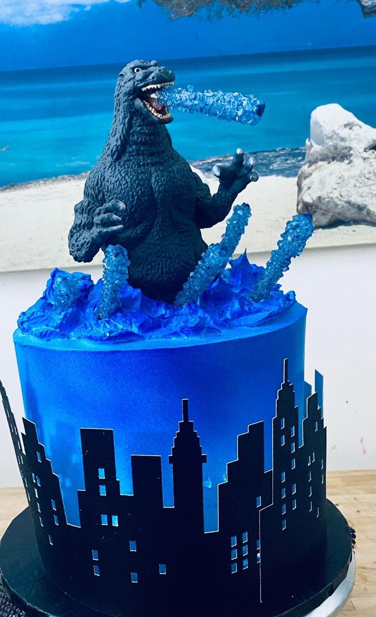 a godzilla figurine on top of a blue and black cake