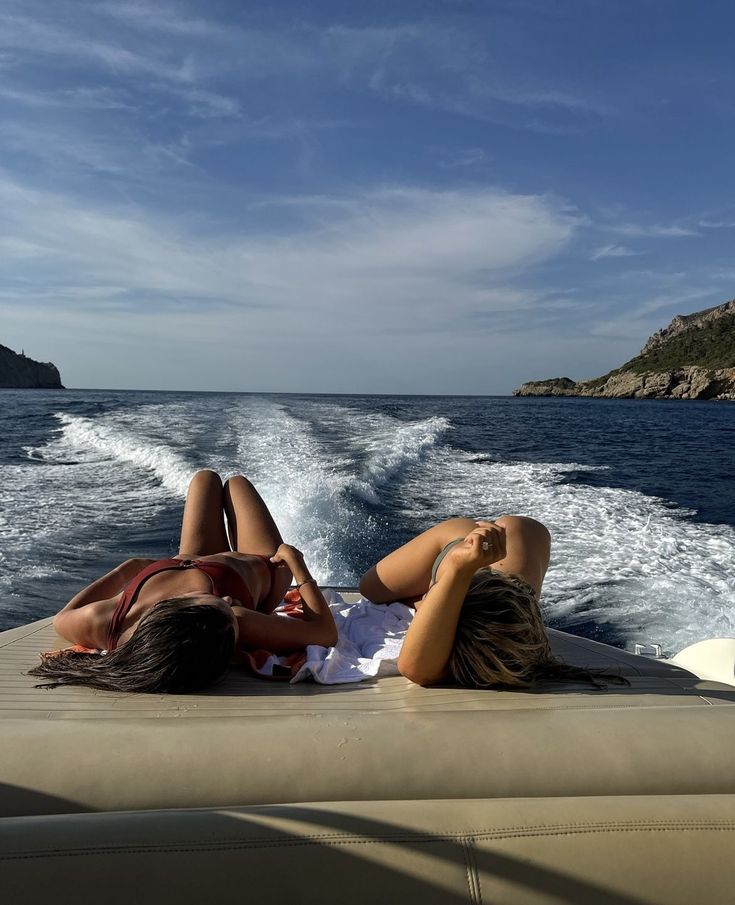 two women laying on the back of a boat