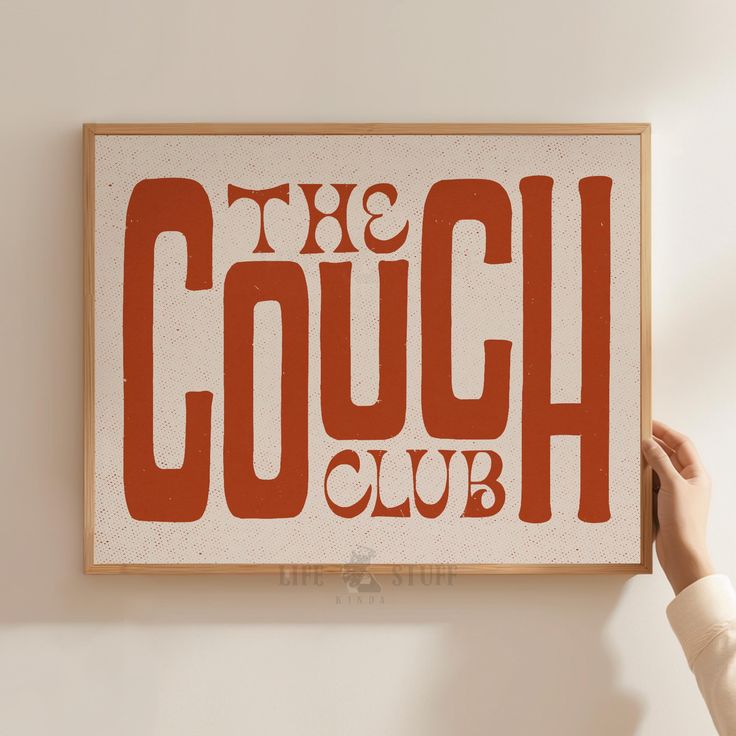 a person holding up a sign that says the couch club on it's wall