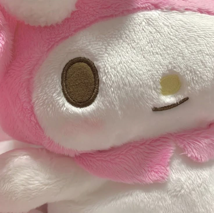 a white and pink stuffed animal with brown eyes