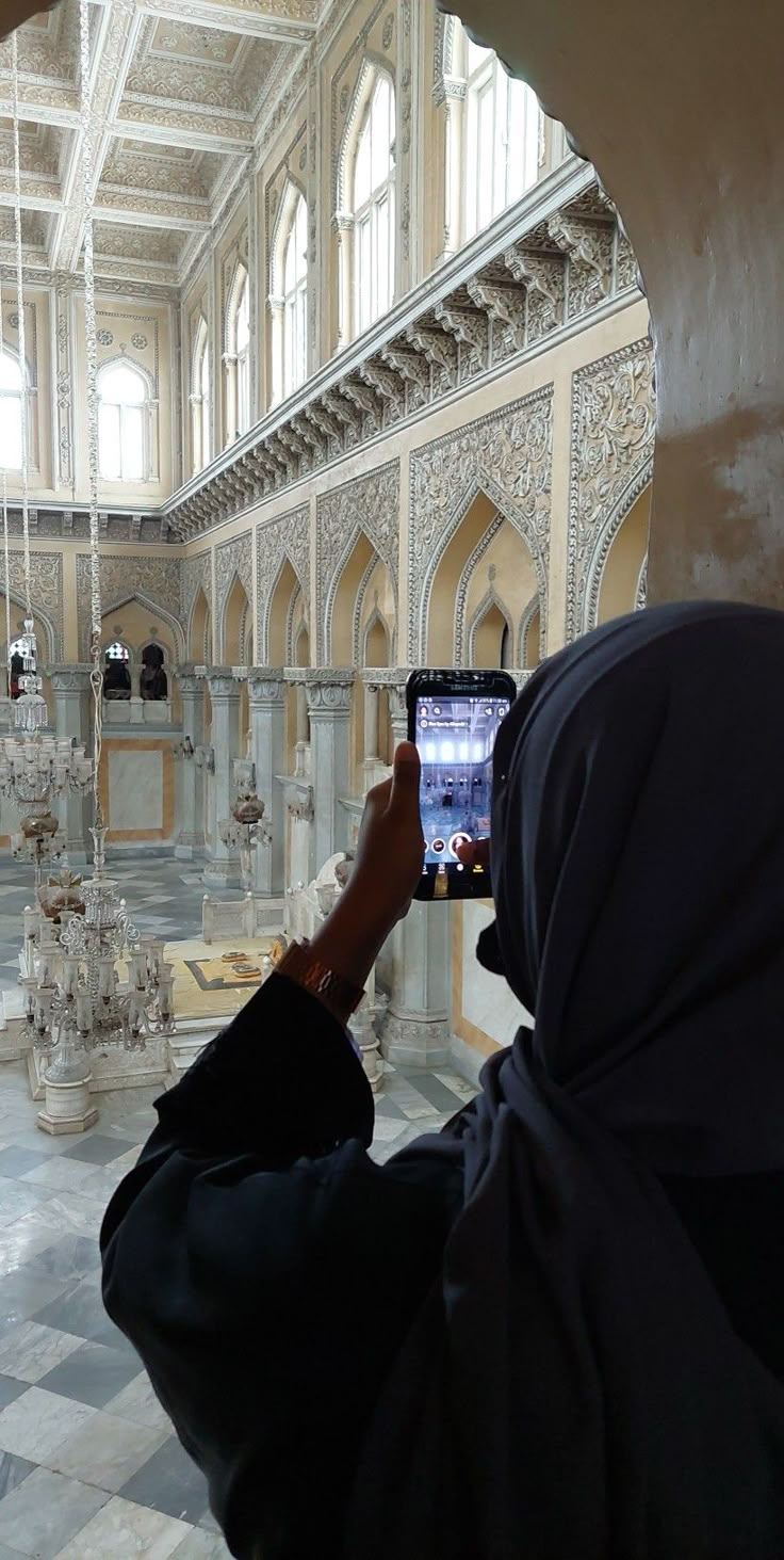 a person taking a photo with a cell phone in a building that looks like a palace