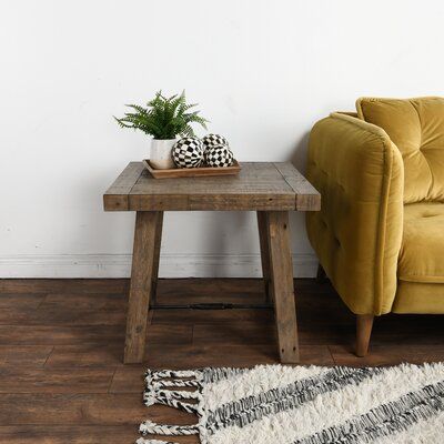 a small table with a potted plant on it next to a couch and rug