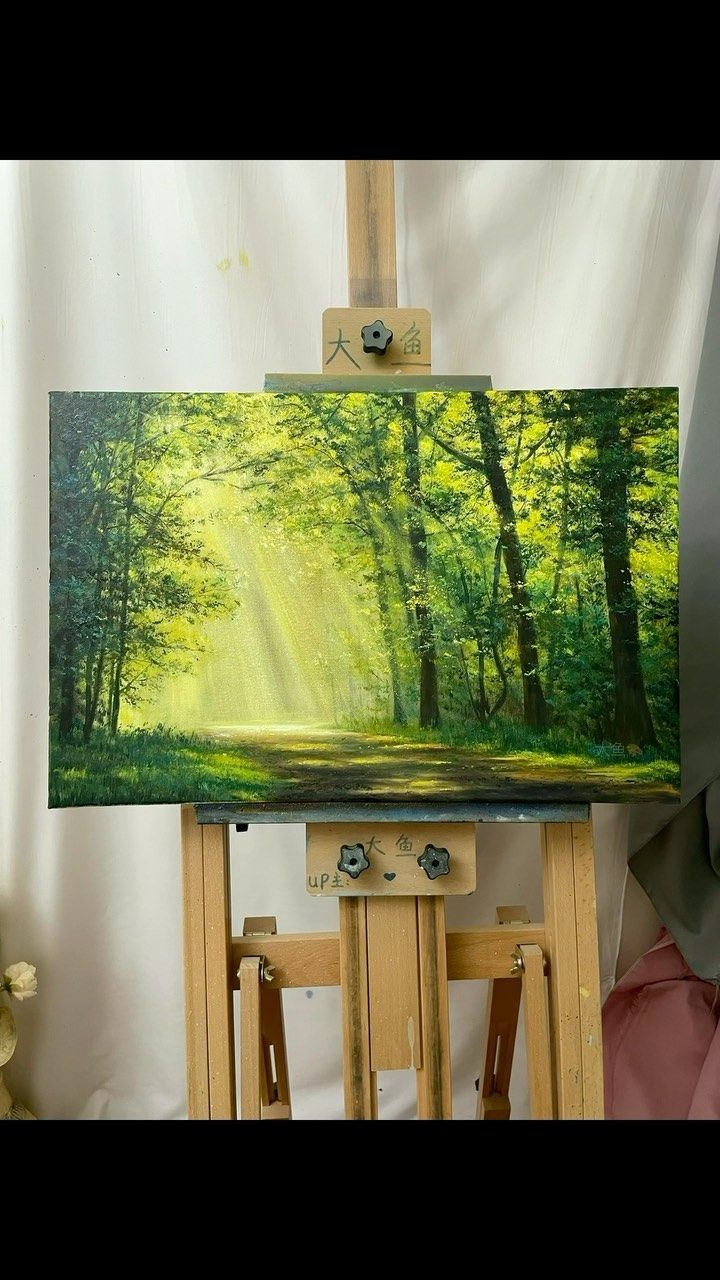 an easel with a painting on it in front of a white wall and trees