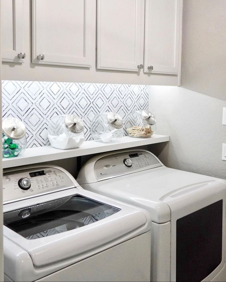 a white washer and dryer sitting next to each other in a room with cabinets