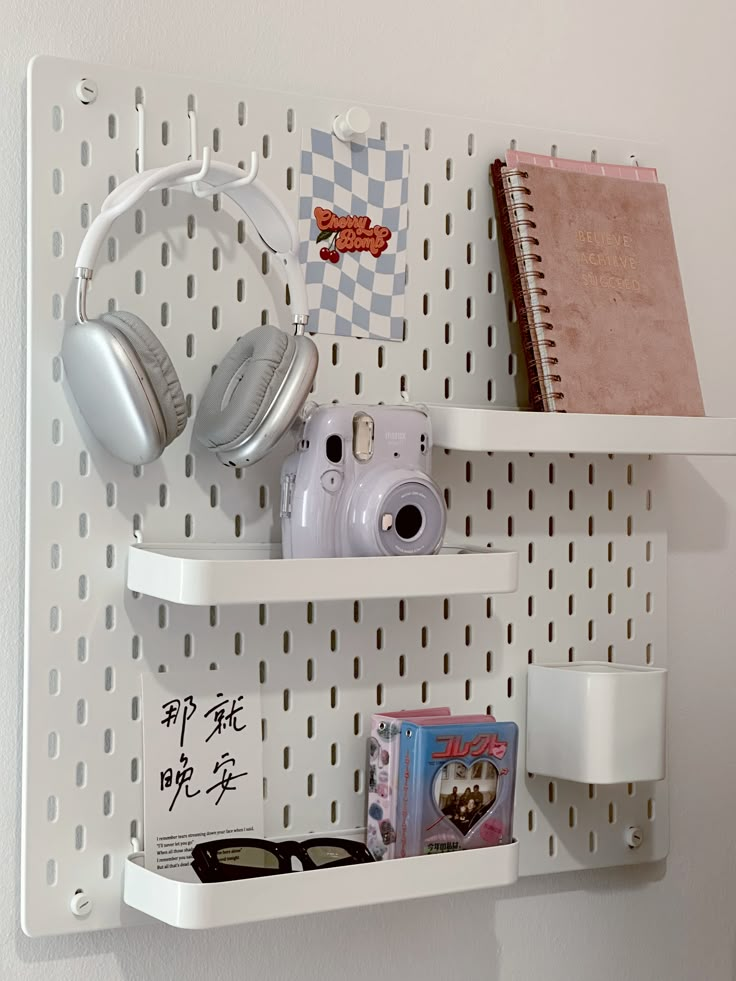 two white shelves with books, headphones and other items on them