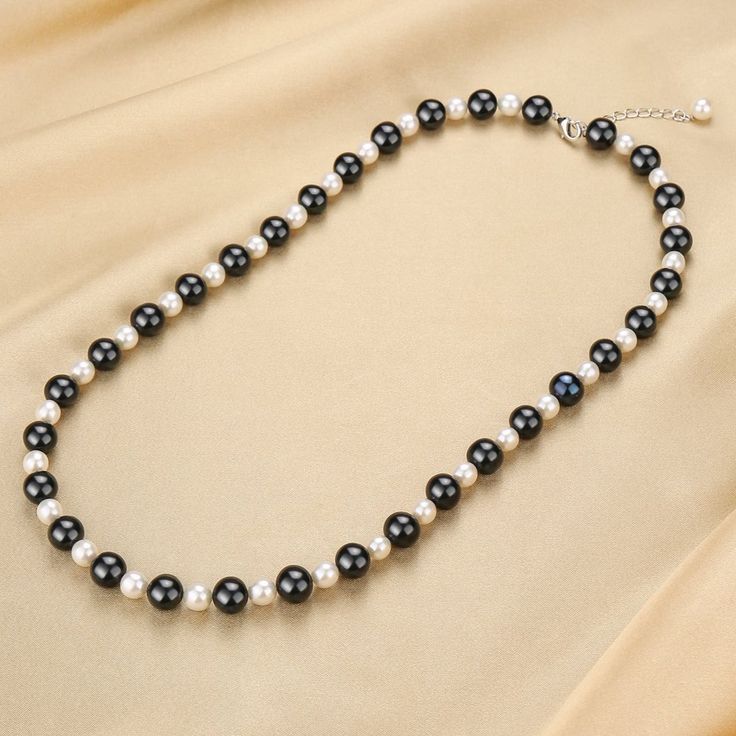 This black and white pearl beaded necklace is a stunning fusion of black and white pearls. This exquisite beaded necklace features a captivating centerpiece: a large 10-11mm colored black pearl, radiating elegance and allure. The sleek and lustrous black pearl is delicately complemented by smaller 6-7mm white freshwater pearls, adding a touch of contrast and sophistication. Crafted with meticulous attention to detail, this necklace exudes a harmonious blend of opulence and refinement. Designed f Pearl Centerpiece, Colors Black And White, Pearl Beaded Necklace, White Pearl Necklace, Pearl Necklaces, Elegant Necklace, White Freshwater Pearl, Pearl Types, Tahitian Pearls