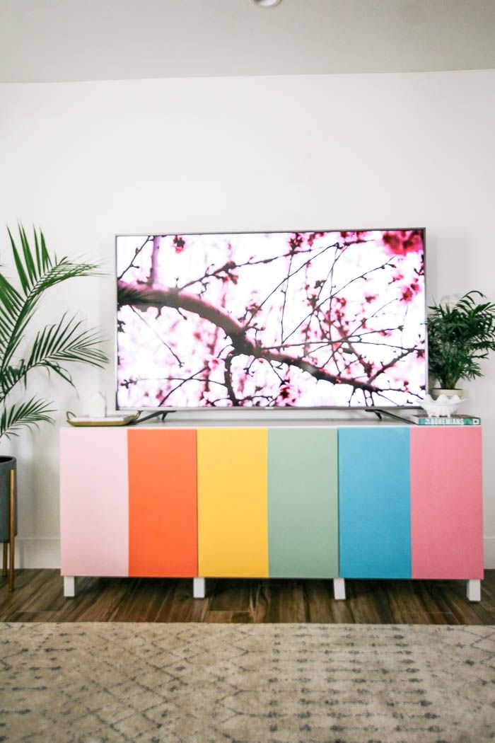 a television that is sitting on top of a cabinet in a living room with plants