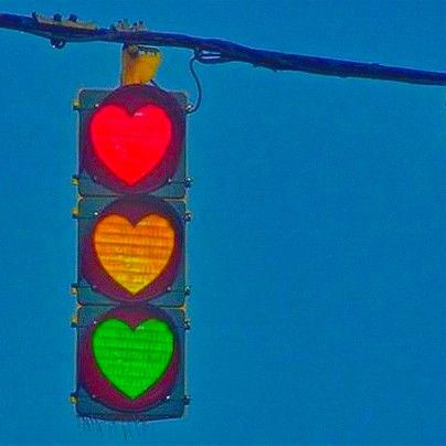 a traffic light with two hearts on it's red and green lights hanging from a wire