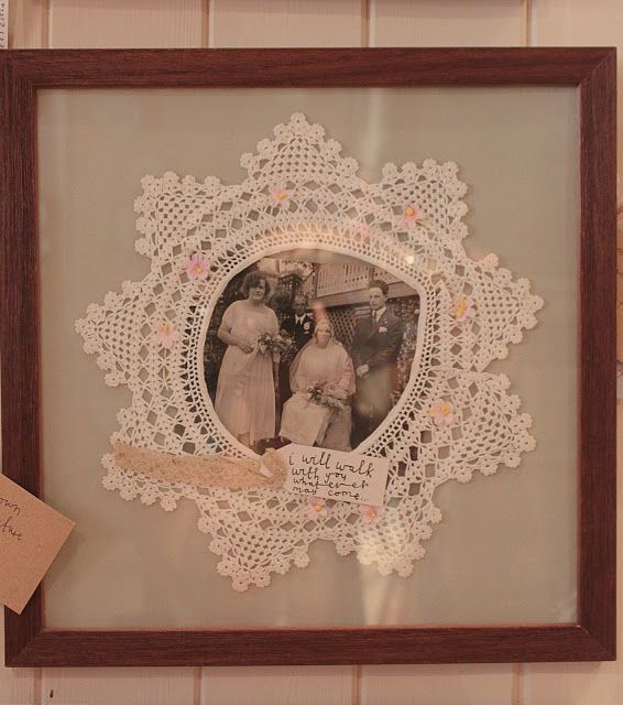 an old photo is hanging on the wall in front of a frame with a lace doily around it