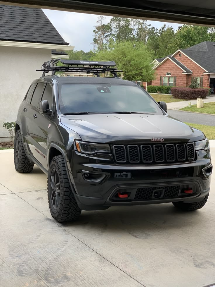 a jeep parked in front of a house with a roof rack on it's top