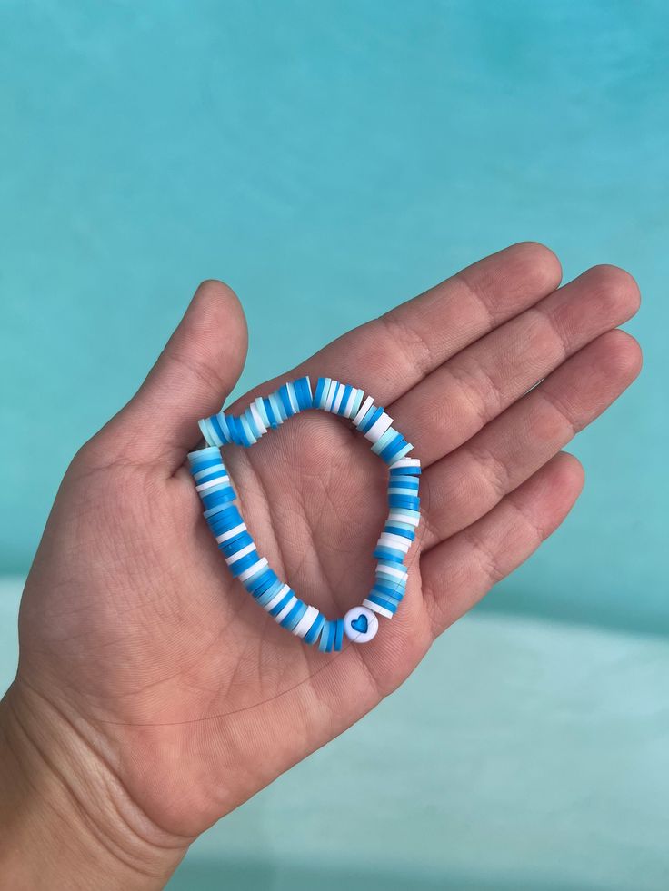 a hand holding a blue and white beaded bracelet