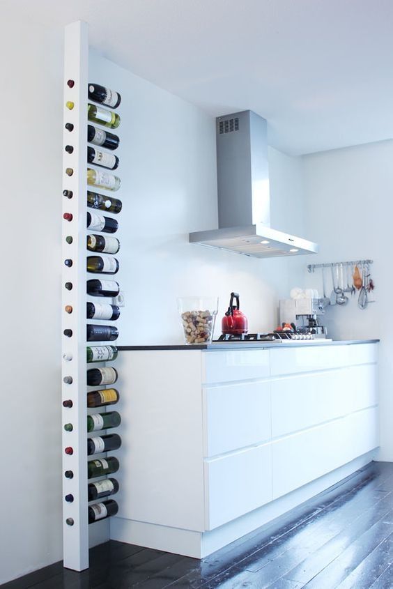 a wine rack in the middle of a kitchen with white cabinets and black flooring