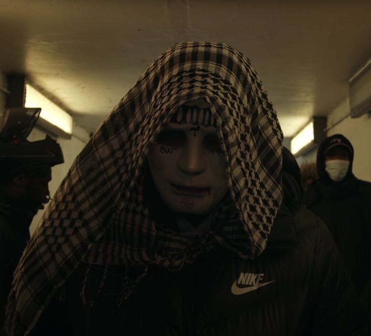 a group of people wearing face paint and covering their faces in hoods, standing together