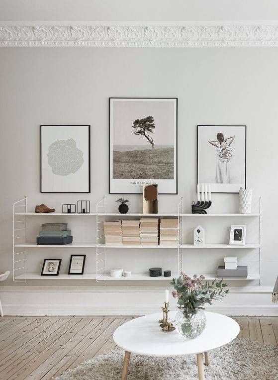 a living room filled with white furniture and pictures on the wall above a coffee table