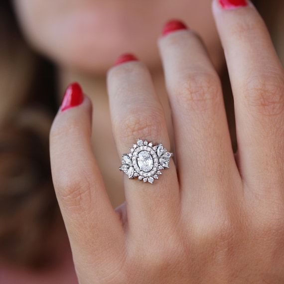 a woman's hand with a diamond ring on her finger and red nail polish