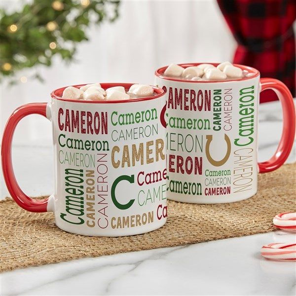 two red and white coffee mugs filled with marshmallows on a table