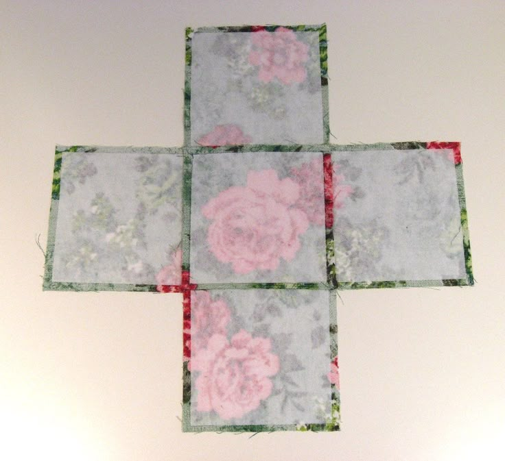 a cross made out of fabric with pink flowers on the top and green trim around it