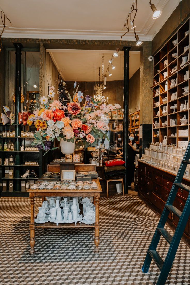 a flower shop filled with lots of vases and flowers next to a wooden table