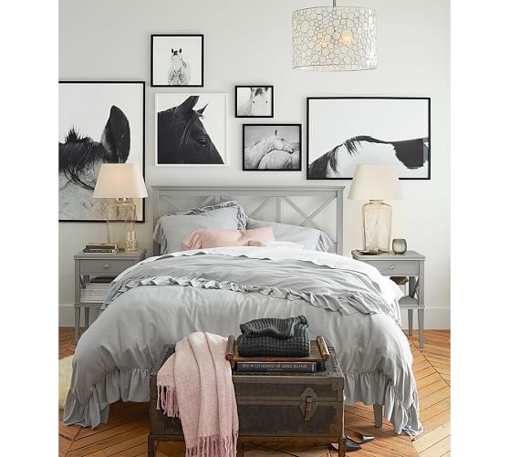 a bedroom with pictures on the wall above the bed, and a suitcase under the bed