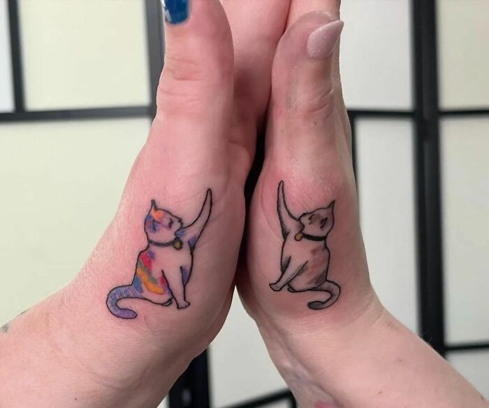 two cats tattoo on both wrist and hand, one with the other cat's tail pointing up