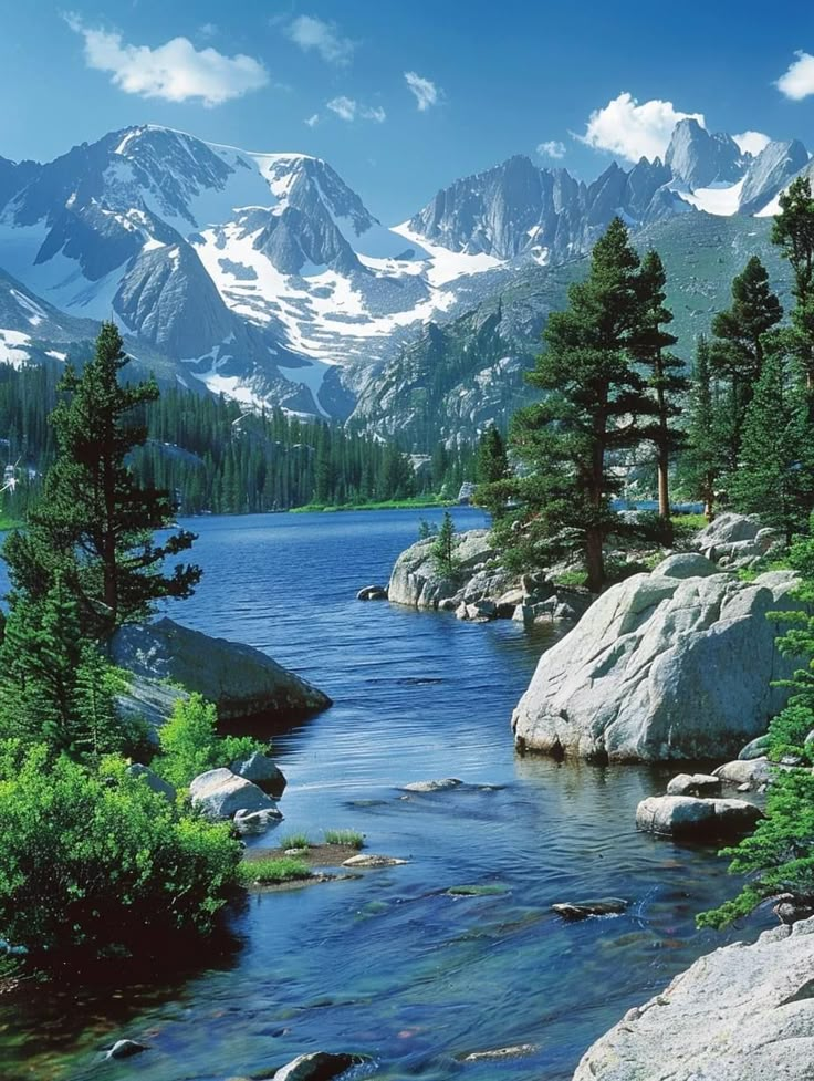 a mountain lake surrounded by trees and rocks with snow capped mountains in the back ground