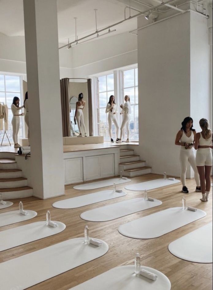 several models in white outfits are walking through a room with wooden floors and large windows