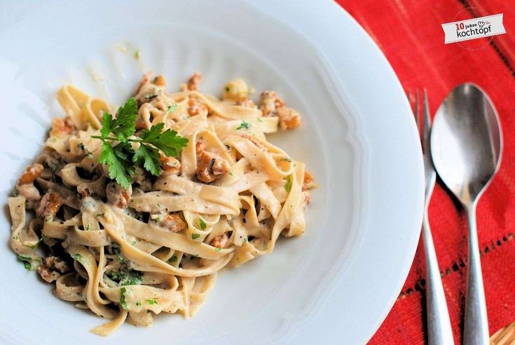 a white plate topped with pasta covered in sauce and parsley next to a fork