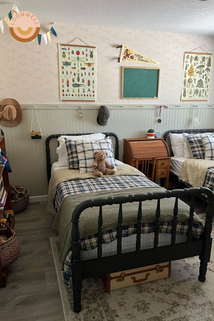 two twin beds in a room with wallpaper and pictures on the walls above them