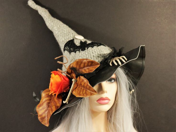 "The Bat and Bone Witch Hat is crocheted and then felted, creating the classic shape. A touch of elegance with a lace bat flying from the dark foliage with the full moon above. The black gauze hat band has a skeleton hand and long bones, with one dangling off the side. An orange rose blooms from the leaves and twigs. Soft but still firm enough to hang on a hook or rest on your table. Felting makes this hat naturally water repellent. This hat is tall and if desired, can be stuffed with paper at t Curved Brim Hat For Halloween Themed Events, Spooky Halloween Costume Hats And Headpieces, Fitted Witchy Hat For Halloween, Halloween Fitted Wide Brim Costume Hat, Fitted Wide Brim Halloween Costume Hat, Halloween Witchy Hat With Wide Brim, Halloween Witchy Wide Brim Hat, Witchy Halloween Costume Hat For Masquerade, Handmade Gothic Costume Hats And Headpieces