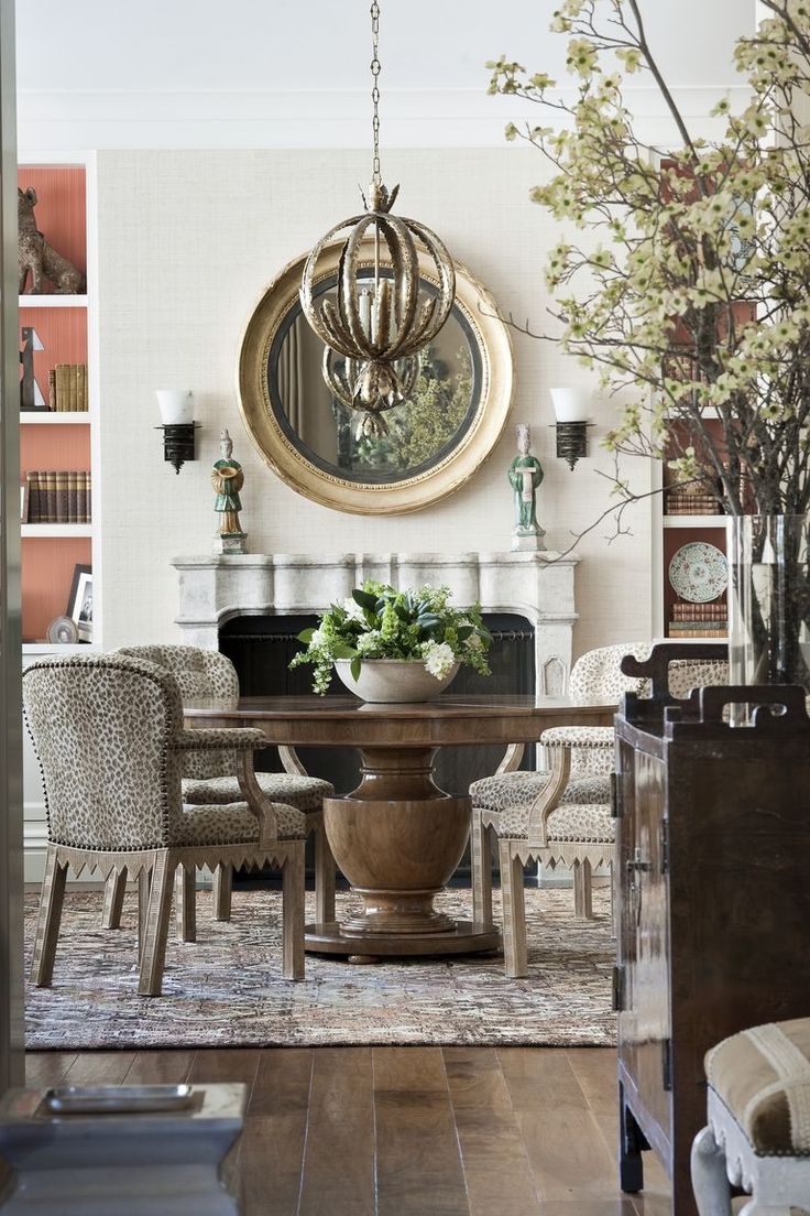 a dining room table with chairs around it and a large mirror hanging above the table