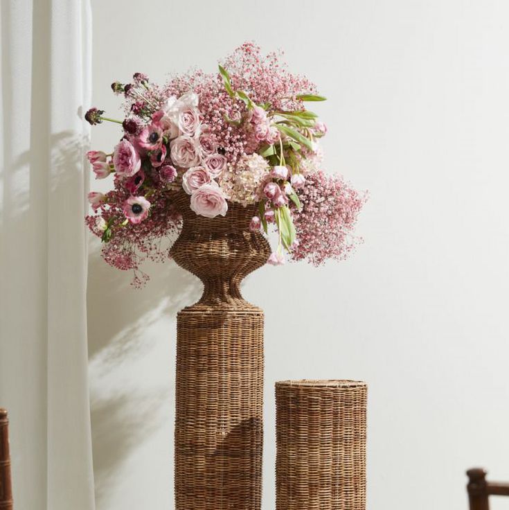 two wicker vases with pink flowers in them