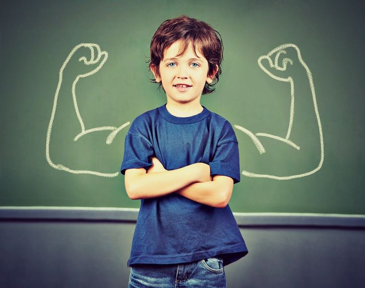 a young boy standing in front of a blackboard with his arms crossed and muscles drawn on it