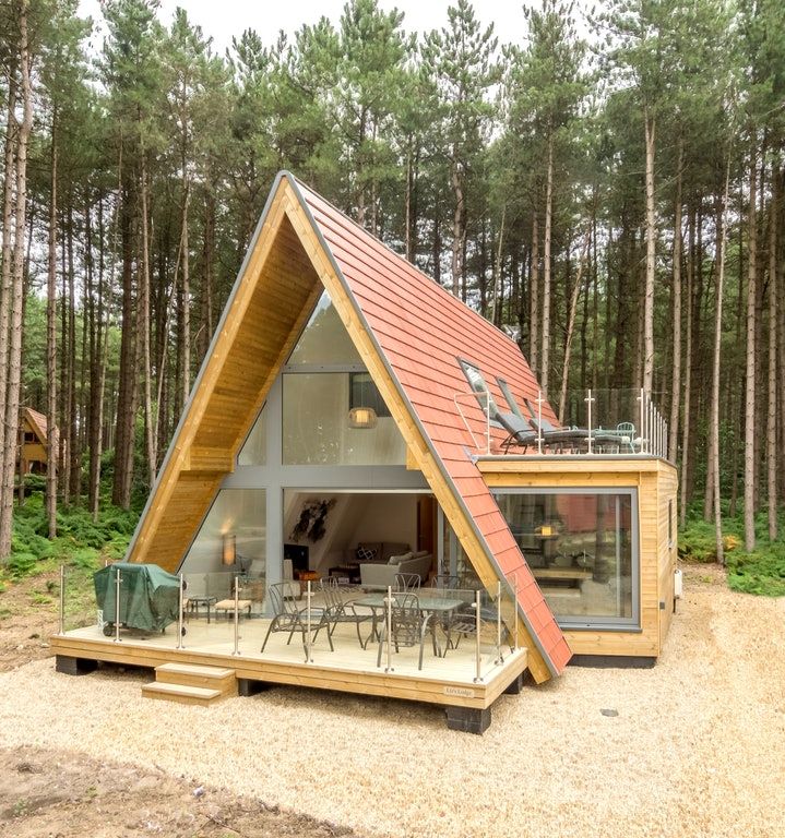 a small wooden cabin in the woods with an open floor plan and roof made from wood