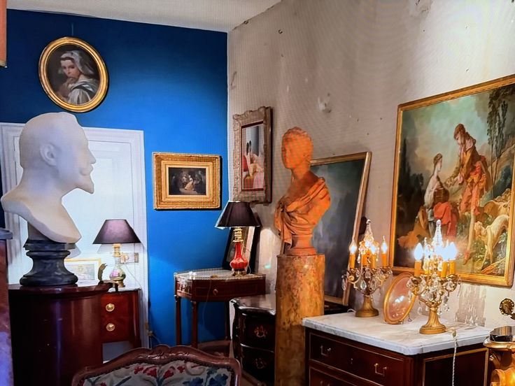 a living room filled with furniture and paintings on the wall above it is a busturine