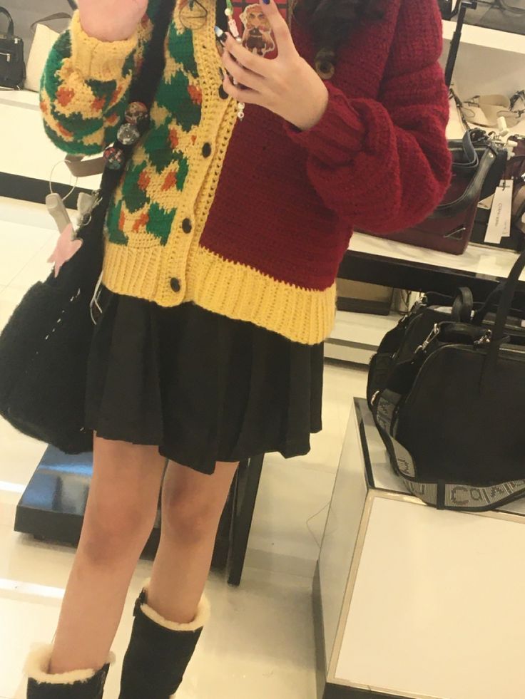 a woman is taking a selfie with her cell phone in the mirror while wearing boots and a sweater