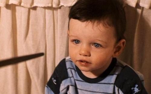 a little boy with green eyes sitting in a chair