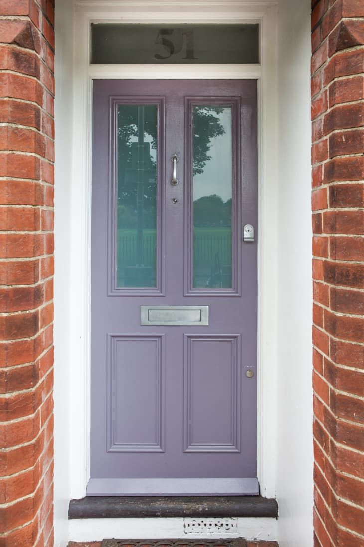 a purple front door with two glass panes on the side and brick pillars around it