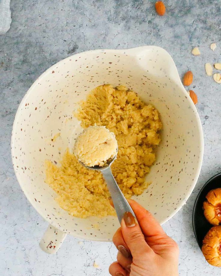 a person holding a spoon in a bowl filled with oatmeal and nuts