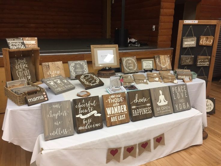 a table topped with lots of wooden signs next to a white table cloth covered table