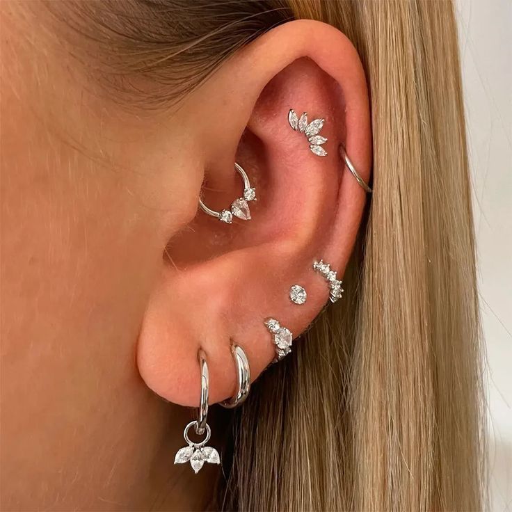 a woman's ear with three different piercings on the top and one behind her ear