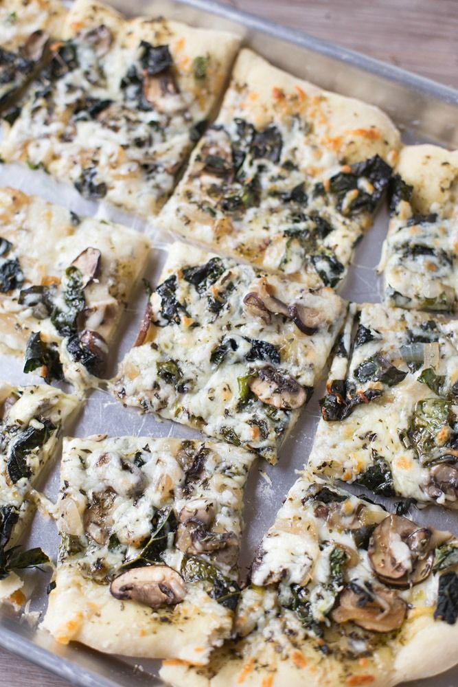 sliced pizza with mushrooms and spinach on a baking sheet, ready to be eaten