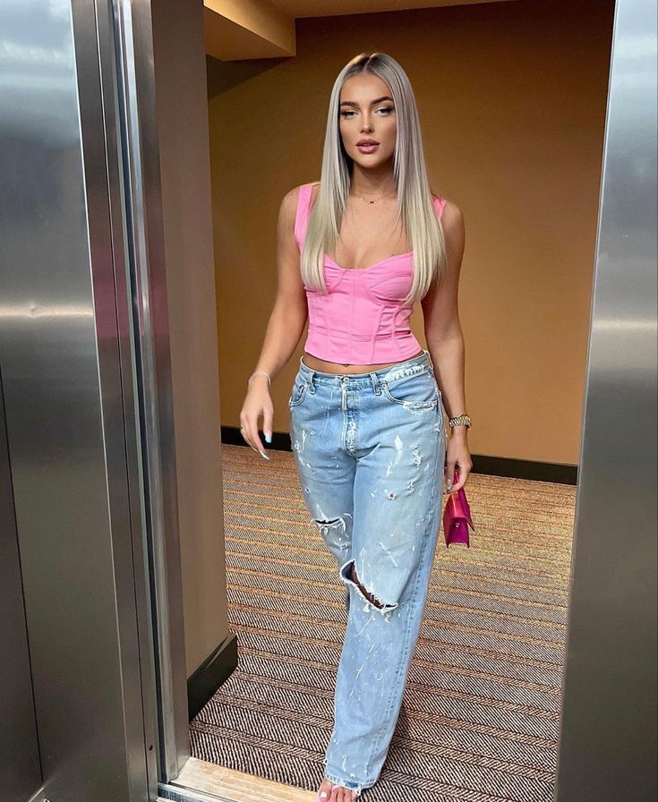 a woman standing in an elevator wearing ripped jeans