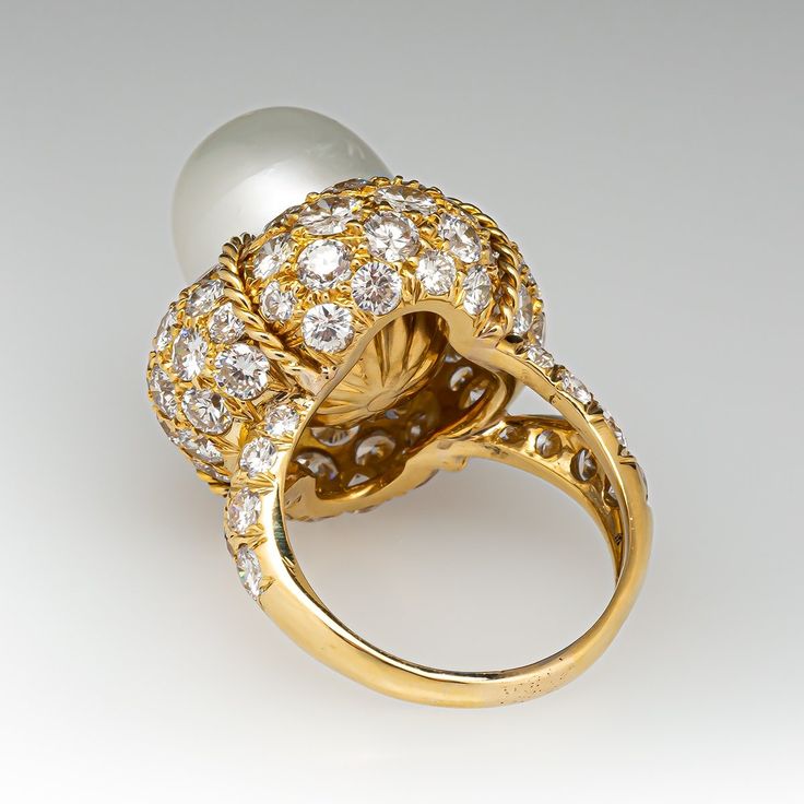 This magnificent cocktail ring is centered with one (1), post set, cultured South Sea pearl. The pearl tops a domed setting is bead set sixty-four (64), bead set, round brilliant cut diamonds. The ring has a split shank design and is accented with seven (7), bead set, round brilliant cut diamonds on each side. The ring measures 21.7mm at the top, rises 18.6mm above the finger, tapering to 2.4mm wide and 1.1mm thick at the base of the shank. The ring is currently size 7. Timeless Formal Pearl Ring With Gemstone, Timeless Pearl Ring For Formal Occasions, Timeless Formal Pearl Gemstone Ring, Formal Oval Pearl Ring, Luxury Domed Jewelry, Luxury Oval Pearl Ring, Formal Pearl Drop Diamond Ring Fine Jewelry, Luxury Round Ring With Pearl Drop, Luxury Formal Pearl Ring With Round Cut