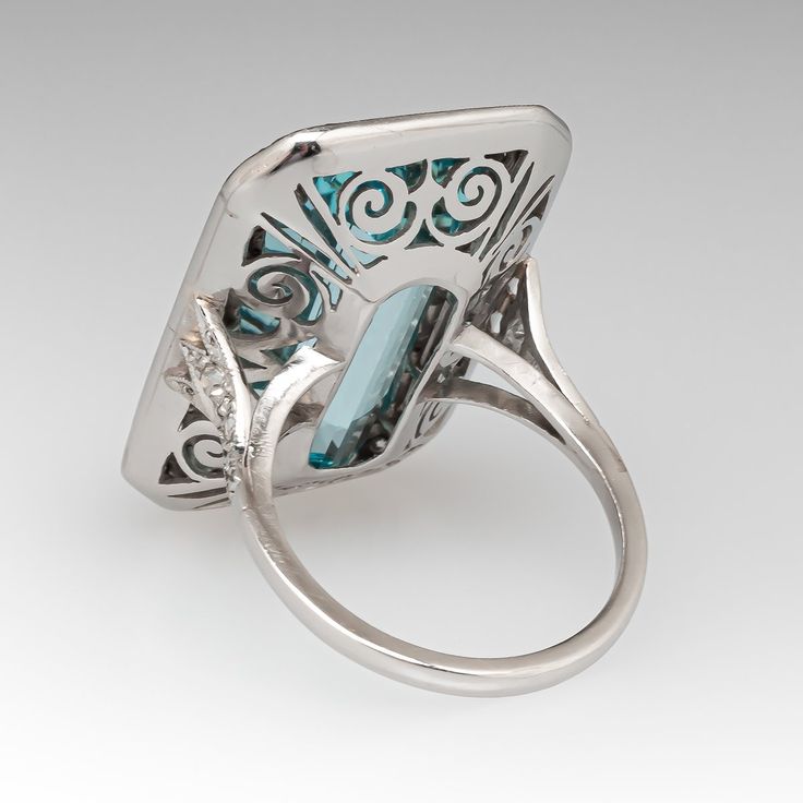 This mazing vintage cocktail ring is centered with one (1), bezel set, emerald cut natural aquamarine that is bordered with thirty-six (36), bead set, round single cut diamonds. The shoulders of the ring are each accented with three (3), bead set, round single cut diamonds. The gemstones are bordered with milgrain edging. The ring measures 28.9mm X 18.7mm at the top, rises 9.1mm above the finger, tapering to 1.7mm wide and 1.3mm thick at the base of the shank. It is currently a size 7. Formal Multi-stone Octagon Rings, Rectangular Topaz Ring In Fine Jewelry Style, Formal Emerald Ring With Rectangular Stone And Bezel Setting, Art Deco Diamond Topaz Ring, Formal Multi-stone Rectangular Ring, Formal Octagon Multi-stone Rings, Art Deco Multi-stone Collectible Jewelry, Luxury Silver Baguette Cut Topaz Ring, Elegant Multi-stone Rectangular Rings